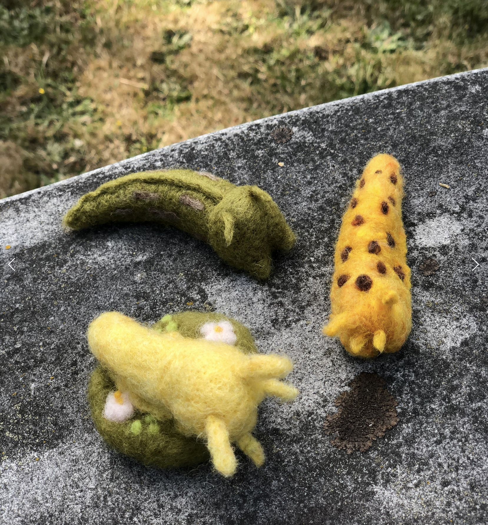 Three felted slugs are pictured. One is light yellow, one is olive green, and one is a yellow banana slug with brown spots.