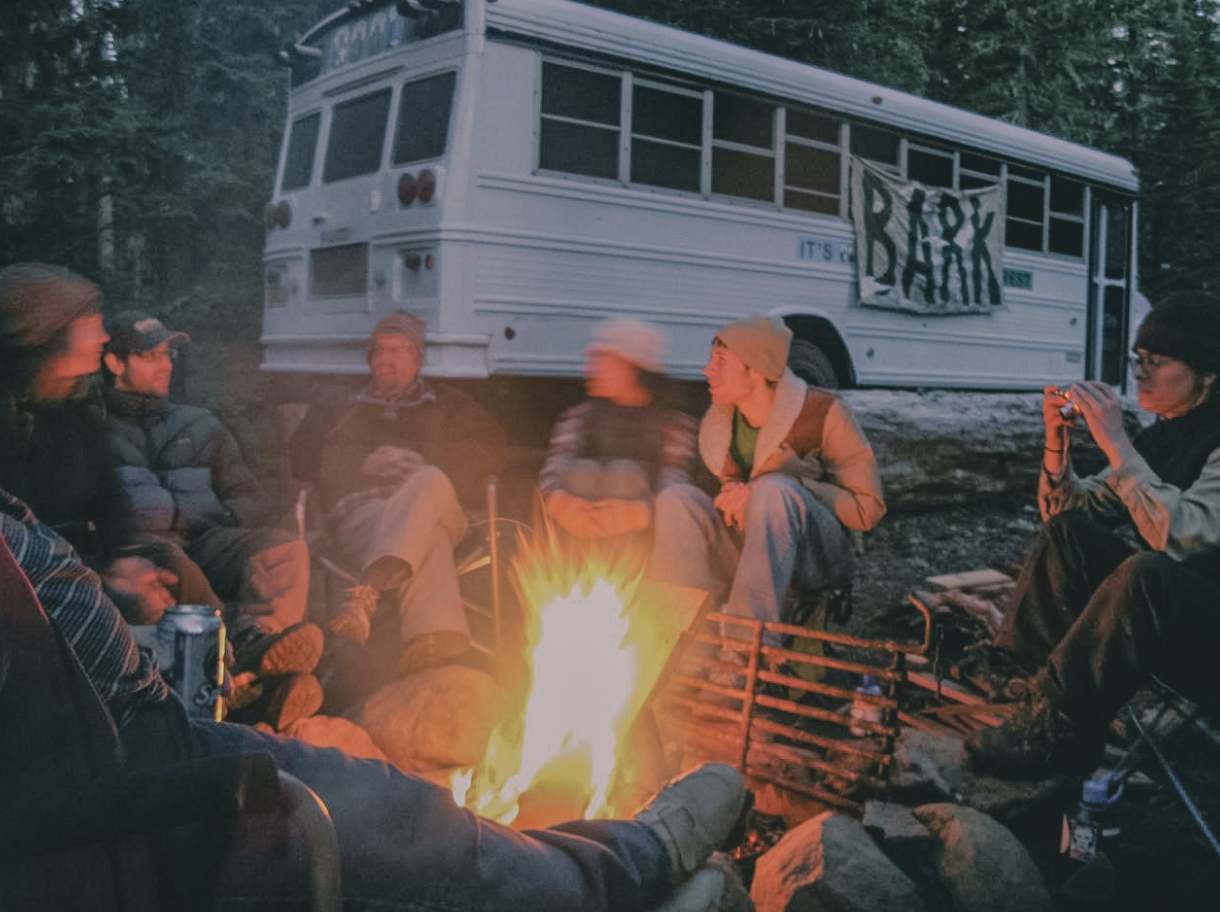 People laughing as they're gathered around campfire