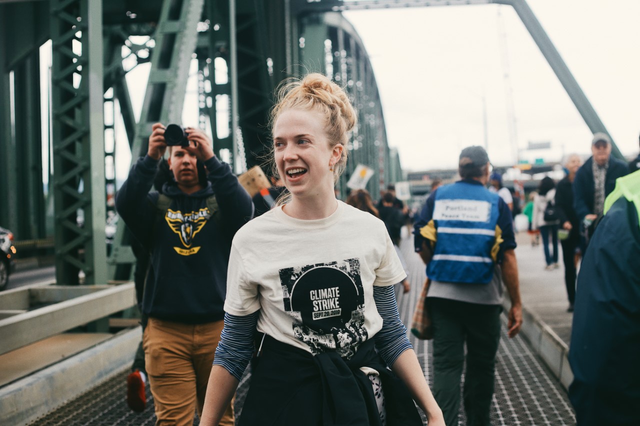 Color photo of Edin on the Hawthorne Bridge during a rally. An individual to her left is taking a photo of her.